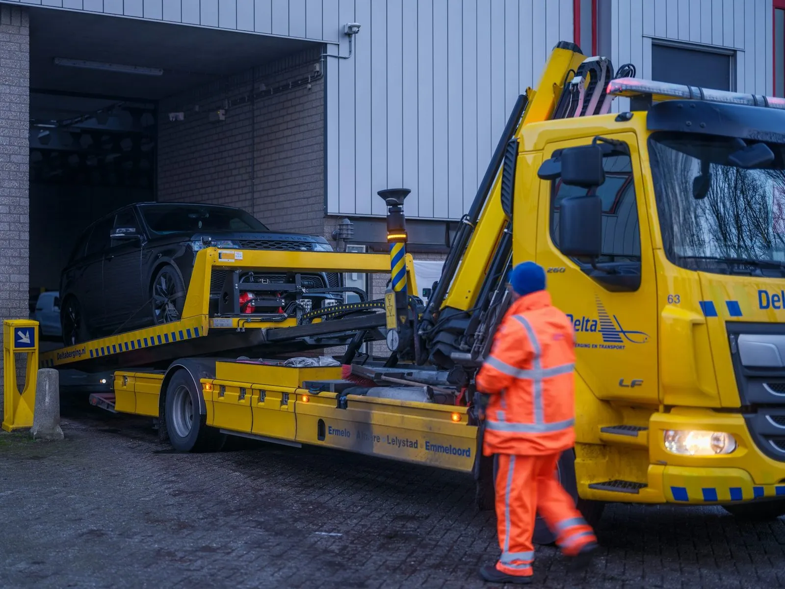 Puksiirauto veab sõiduautot platvormil töökotta